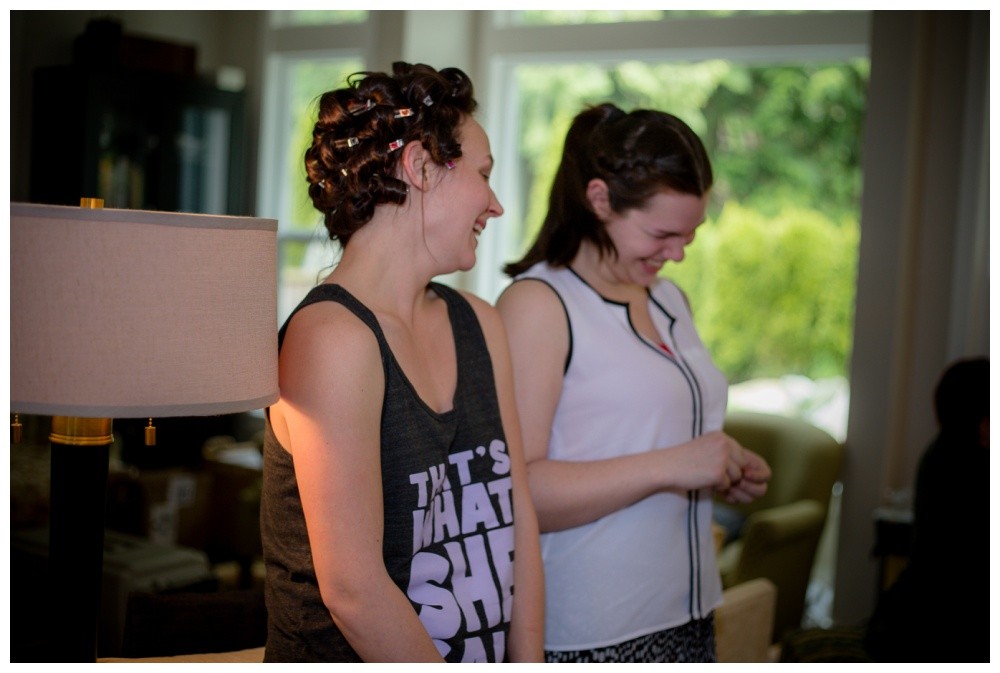 Bride and bridesmaid laughing while getting ready 