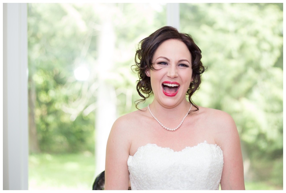 Bride laughing while getting ready and putting her dress on.