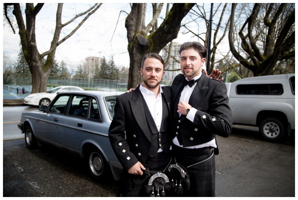 Groom and best man embrace in the parking lot before the ceremony. 