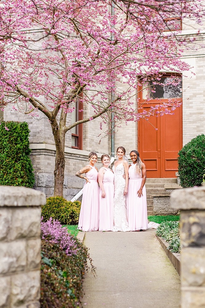 Bride and bridesmaids pose for group photo under a blossoming cherry tree in downtown Victoria BC