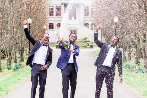 Groom and groomsmen celebrate by spraying a bottle of champagne on wedding day