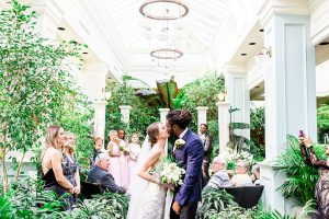 Bride and groom kiss during wedding processional at the Spring Prelude garden at Buchart Gardens